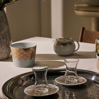 صلصال طقم تمرة بالتعاون مع رزان العزوني سترايبس المؤلف من فنجانين عربيين للشاي مع صحنيهما باللون الذهبي